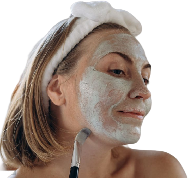 Woman with a white clay mask applied to her face, wearing a soft terry headband — the prep step that turns a sculpted cheekbone from 'makeup sitting on a face' into 'the face itself'